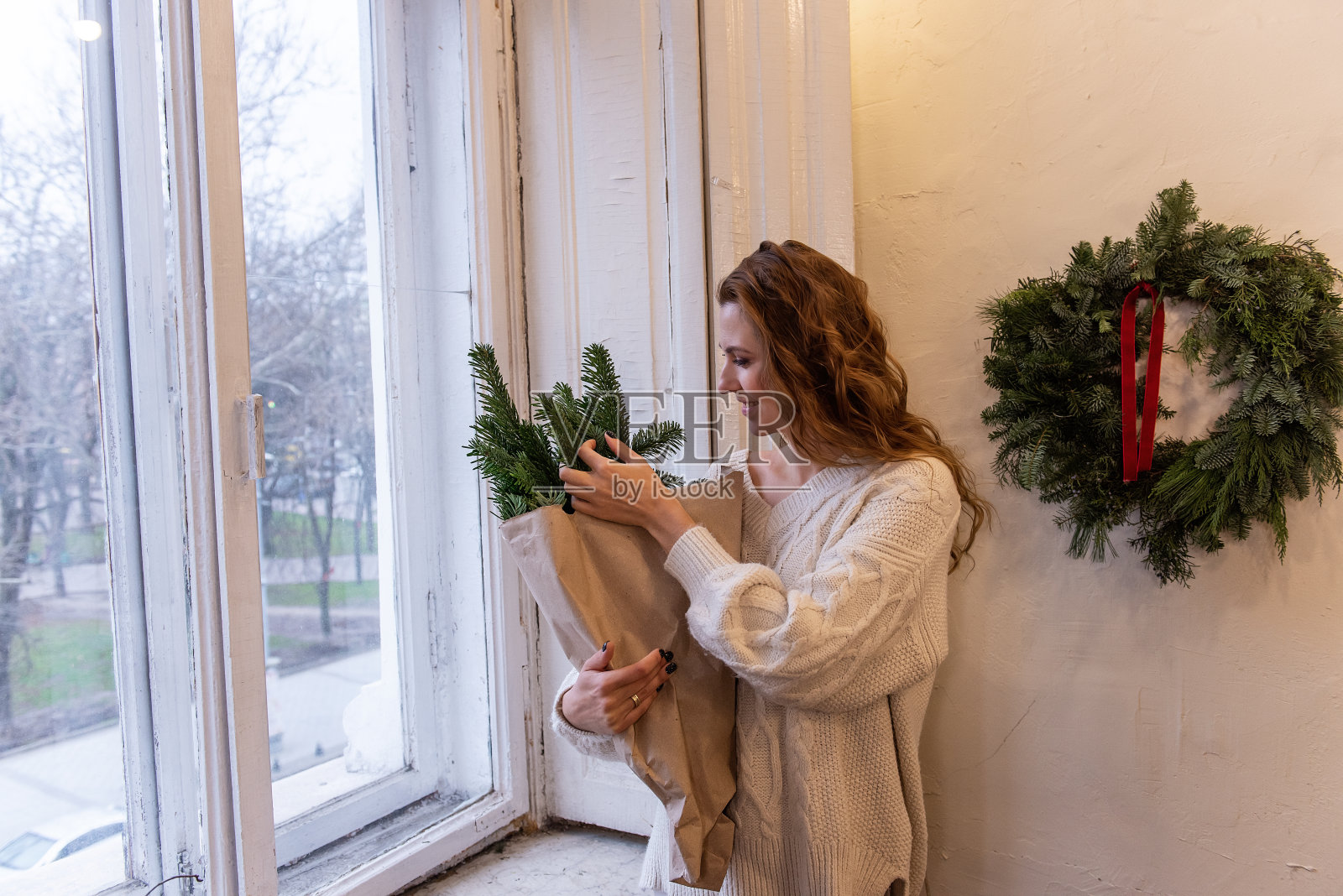 穿着白色针织毛衣的年轻女子的肖像，手里拿着环保的冬季花束照片摄影图片