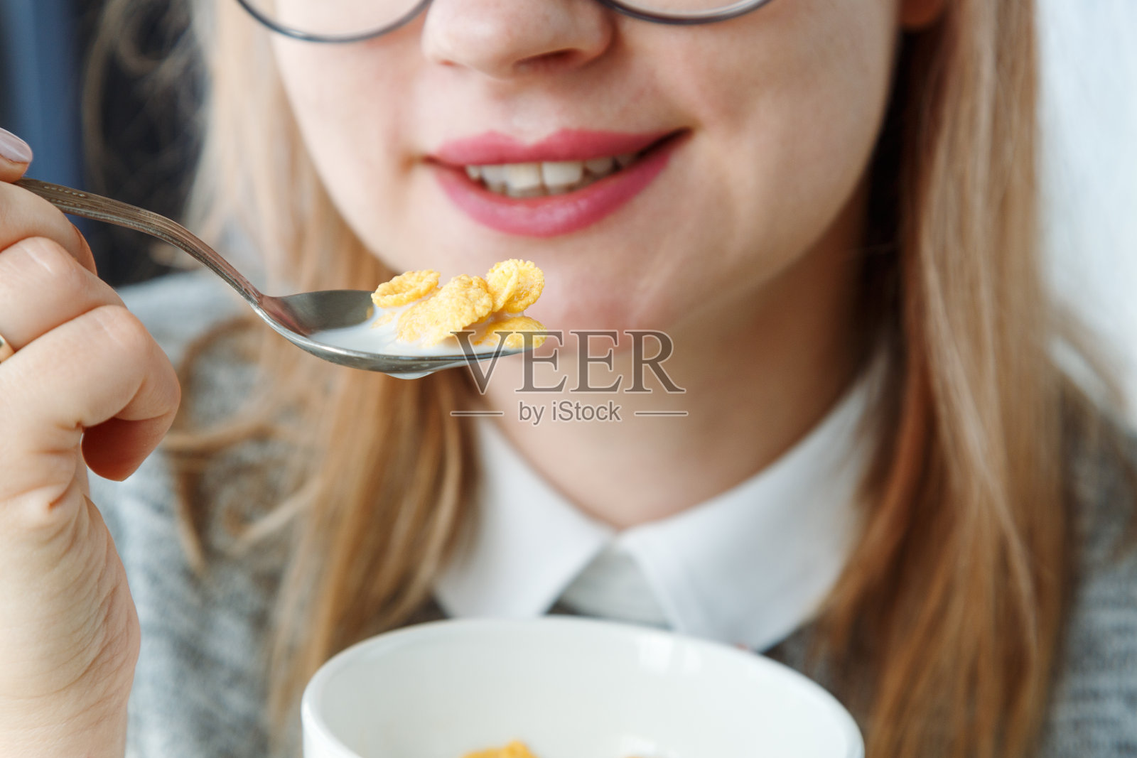 特写镜头:早餐时用牛奶蘸着玉米片大口大口地吃，面目全非的女人。照片摄影图片