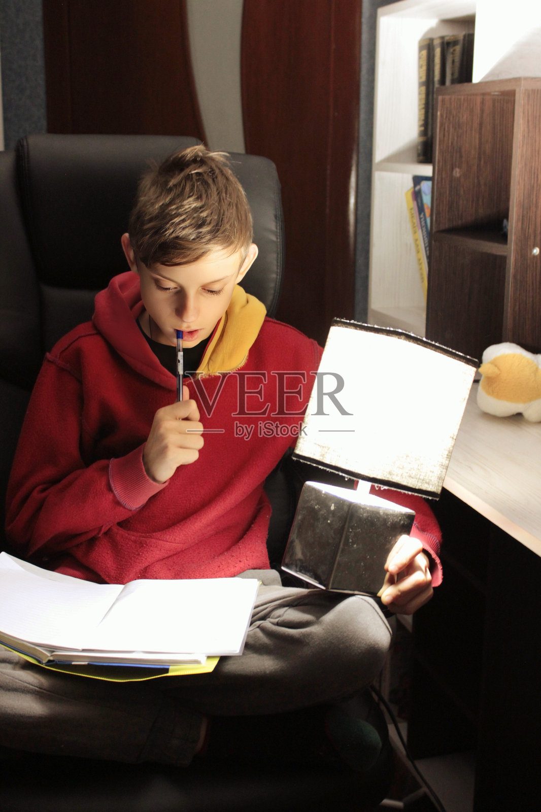 一个男孩晚上在一盏台灯旁学习照片摄影图片