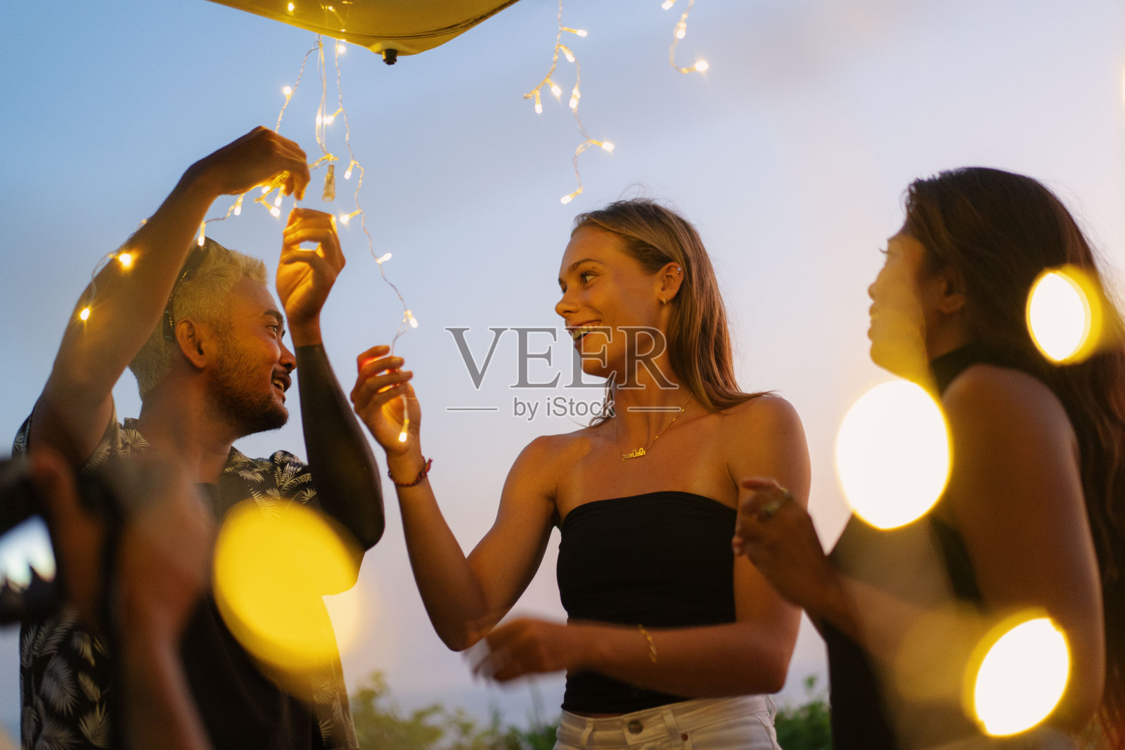 黄昏时分，一群朋友在一辆面包车的后面挂起闪烁的灯照片摄影图片