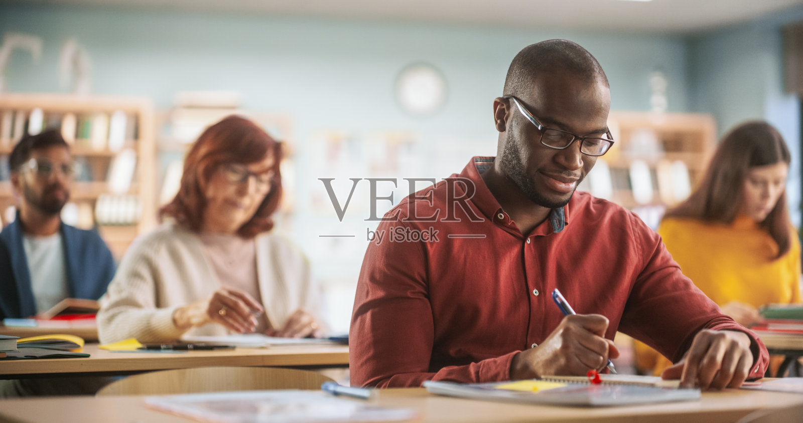 黑人青年在学校的成人教育培训课程中学习新技能。多样的成熟学生在课堂上学习，在课本上阅读，在笔记本上书写。照片摄影图片