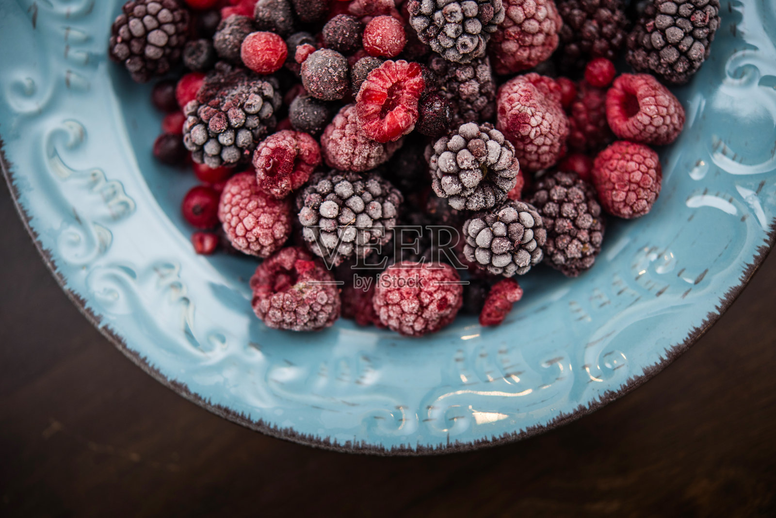 在蓝色陶瓷盘子上混合冷冻浆果照片摄影图片