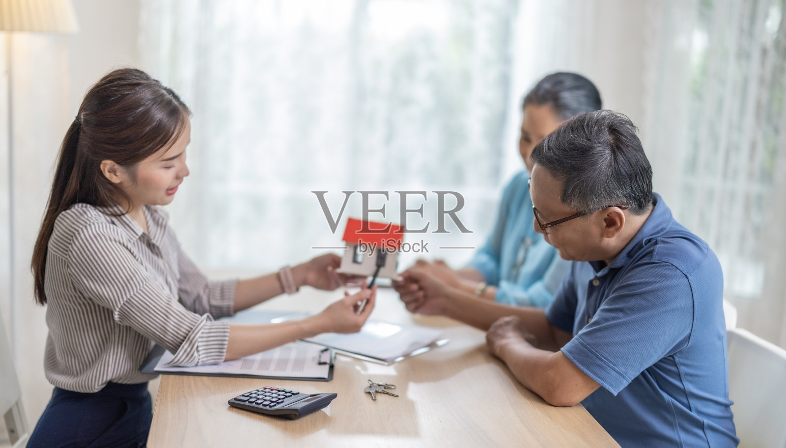 老年夫妇对退休住房购买合同感到满意，女销售员移交钥匙照片摄影图片