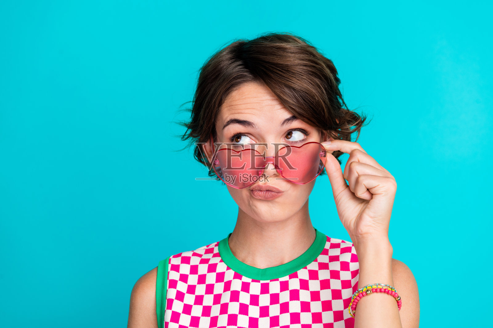 年轻女士噘嘴沉思的照片，新奇的介绍新时尚设计时代孤立的海蓝宝石色背景照片摄影图片