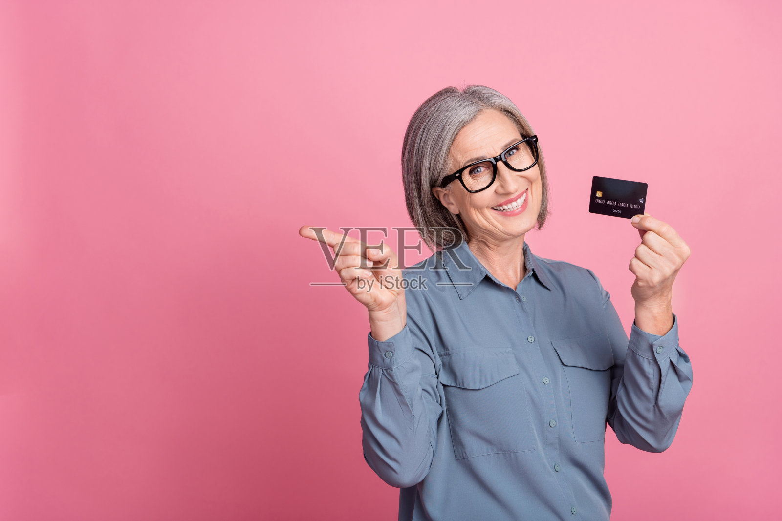 开朗满意的高级女士穿着时髦的衣服手臂展示空的空间购物销售孤立在粉红色的背景照片照片摄影图片