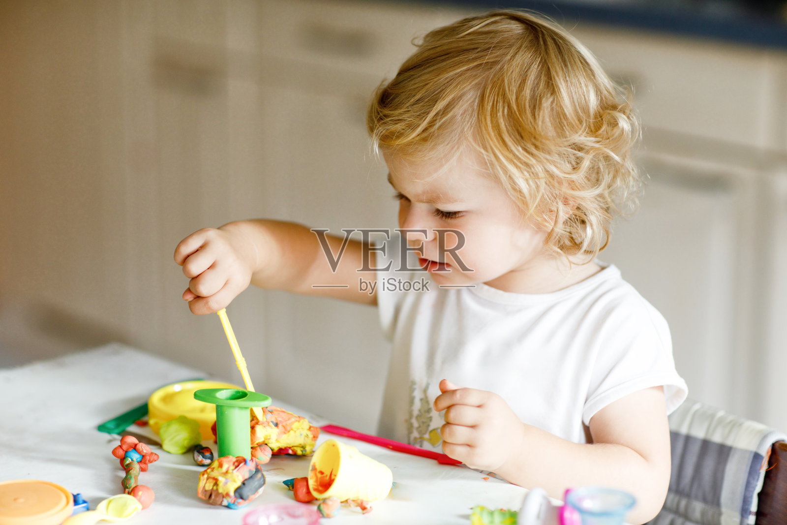可爱可爱的小女孩用五颜六色的粘土。健康的宝宝正在用橡皮泥制作玩具。幼儿陶土造型和学习照片摄影图片