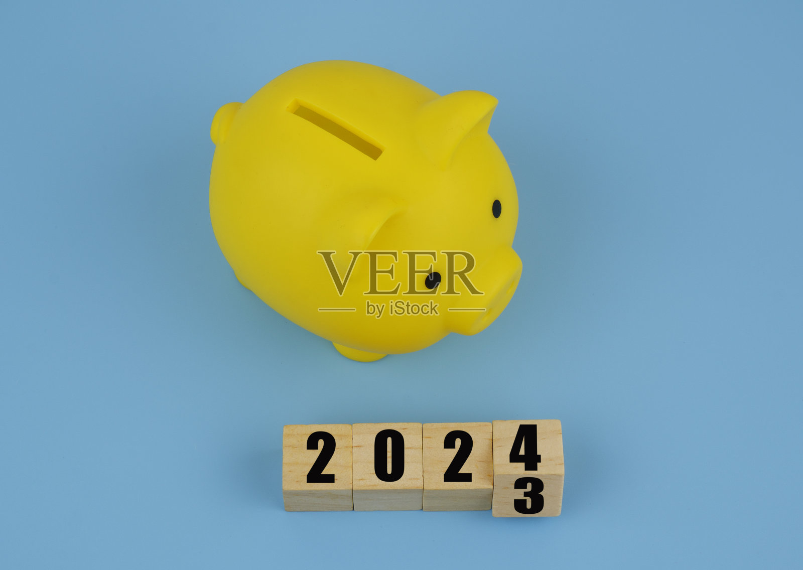 黄色的存钱罐和蓝色背景上的立方体上的数字2023和2024。照片摄影图片