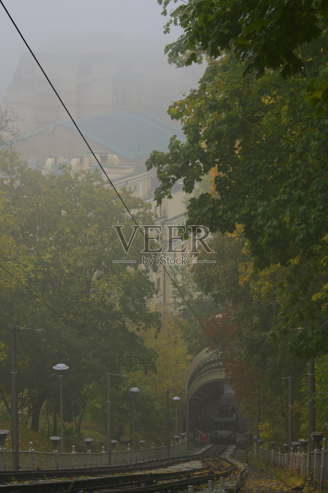 下站索道车厢神秘的雾蒙蒙景观。公园里秋天色彩斑斓的树。基辅的阴雨天气。乘客们正等着出发去上站照片摄影图片