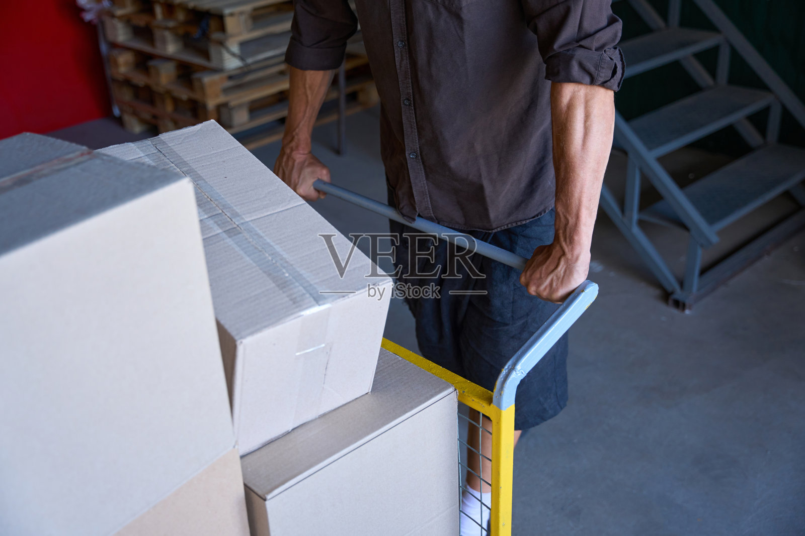 一个手臂强壮的人正在搬运许多箱子照片摄影图片