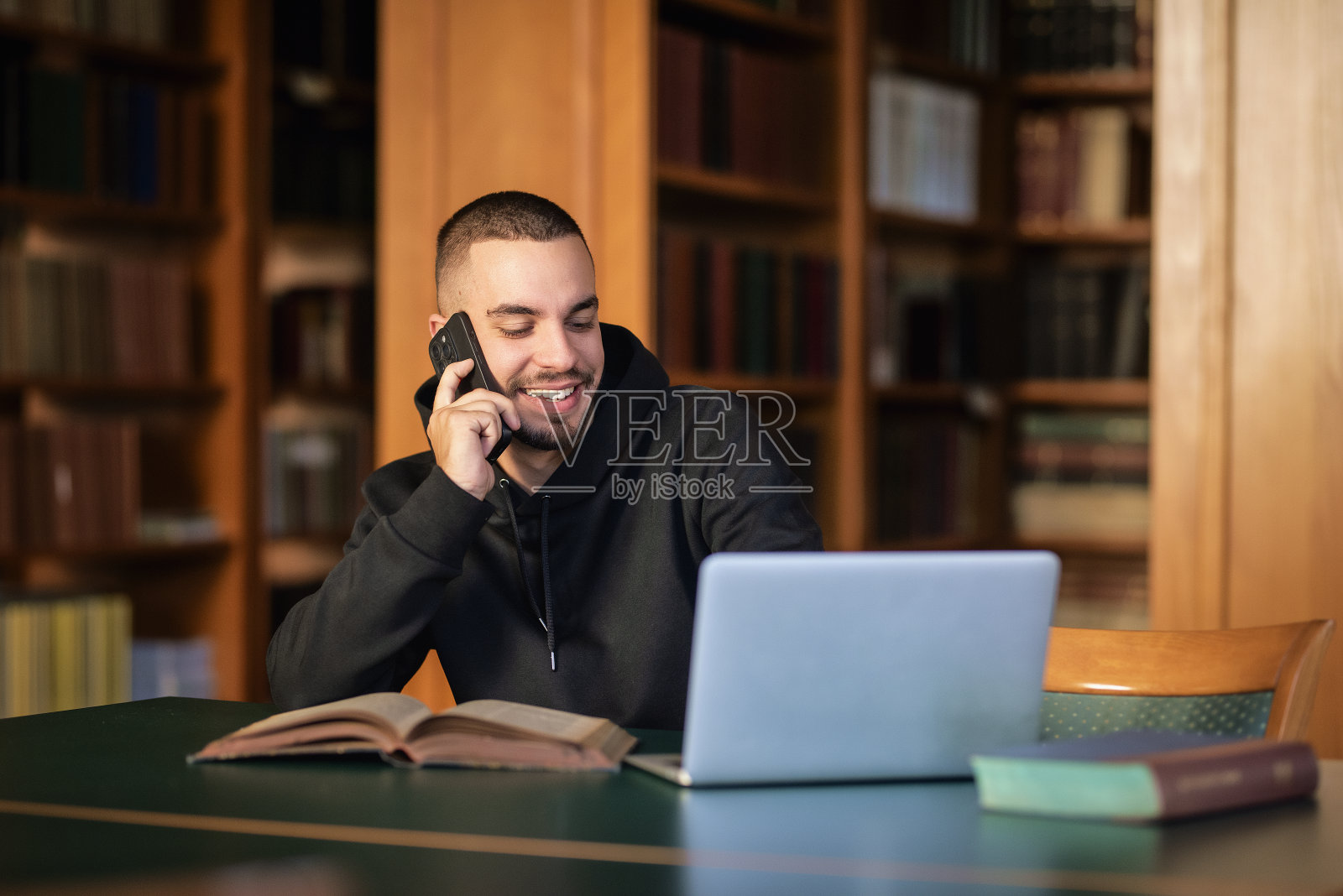 快乐的人坐在大学图书馆，用手机和笔记本照片摄影图片