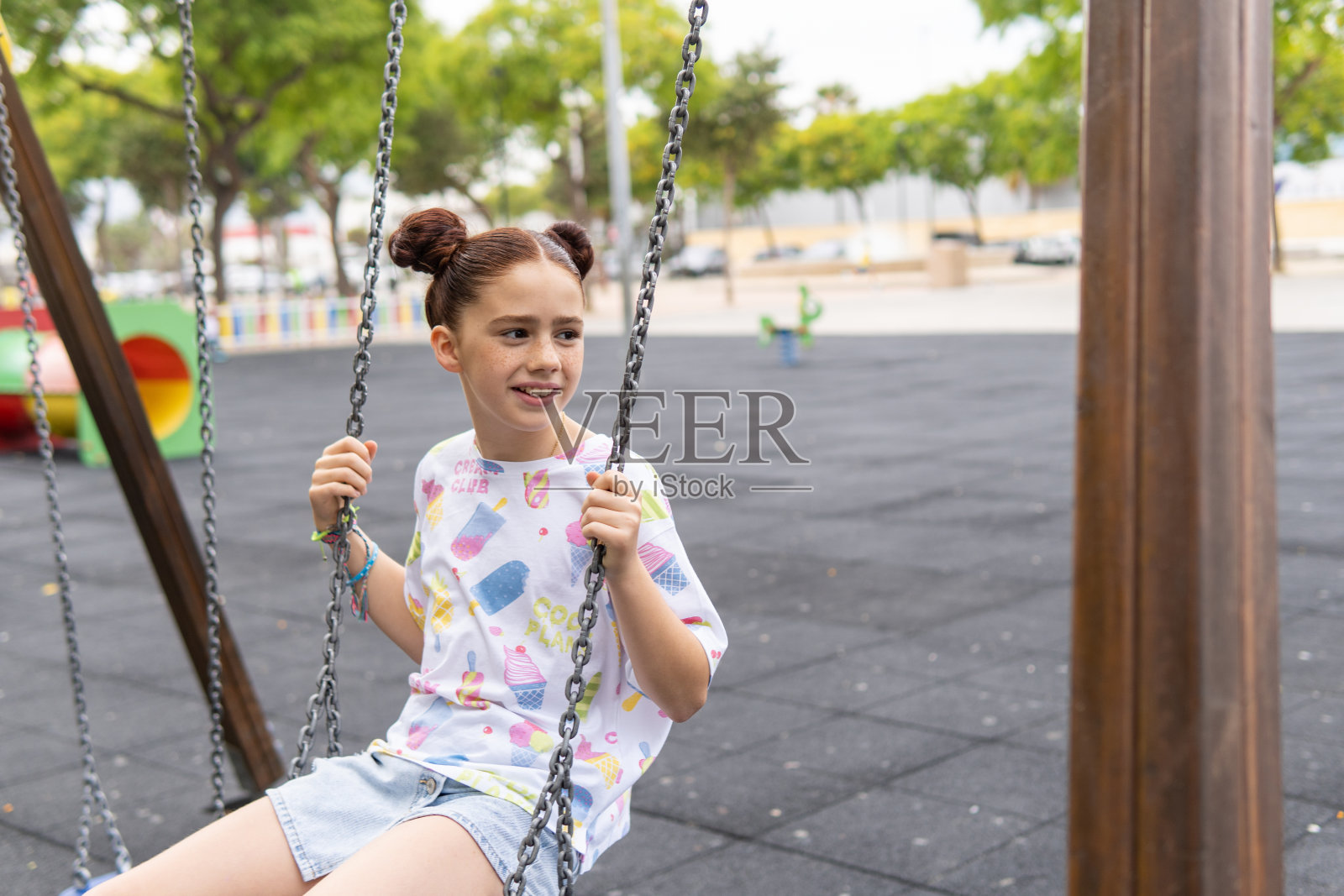 一个长着雀斑的红发女孩在操场上荡秋千时笑的画像。幸福和快乐的概念照片摄影图片