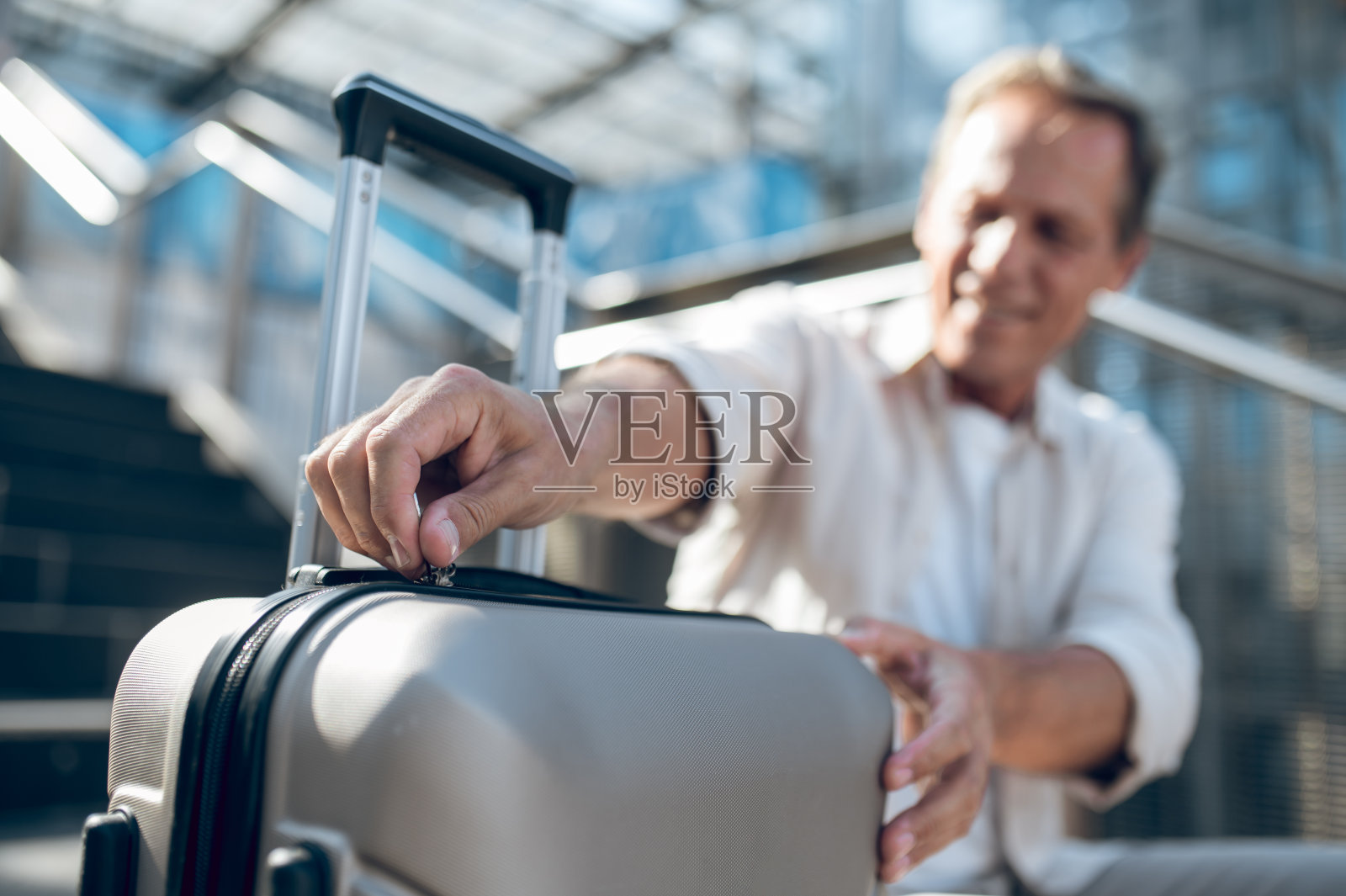 穿衬衫的中年男子坐在街上打开他的手提箱。照片摄影图片