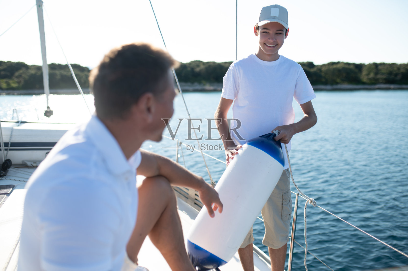 儿子和爸爸驾着游艇，看起来很开心很满足照片摄影图片