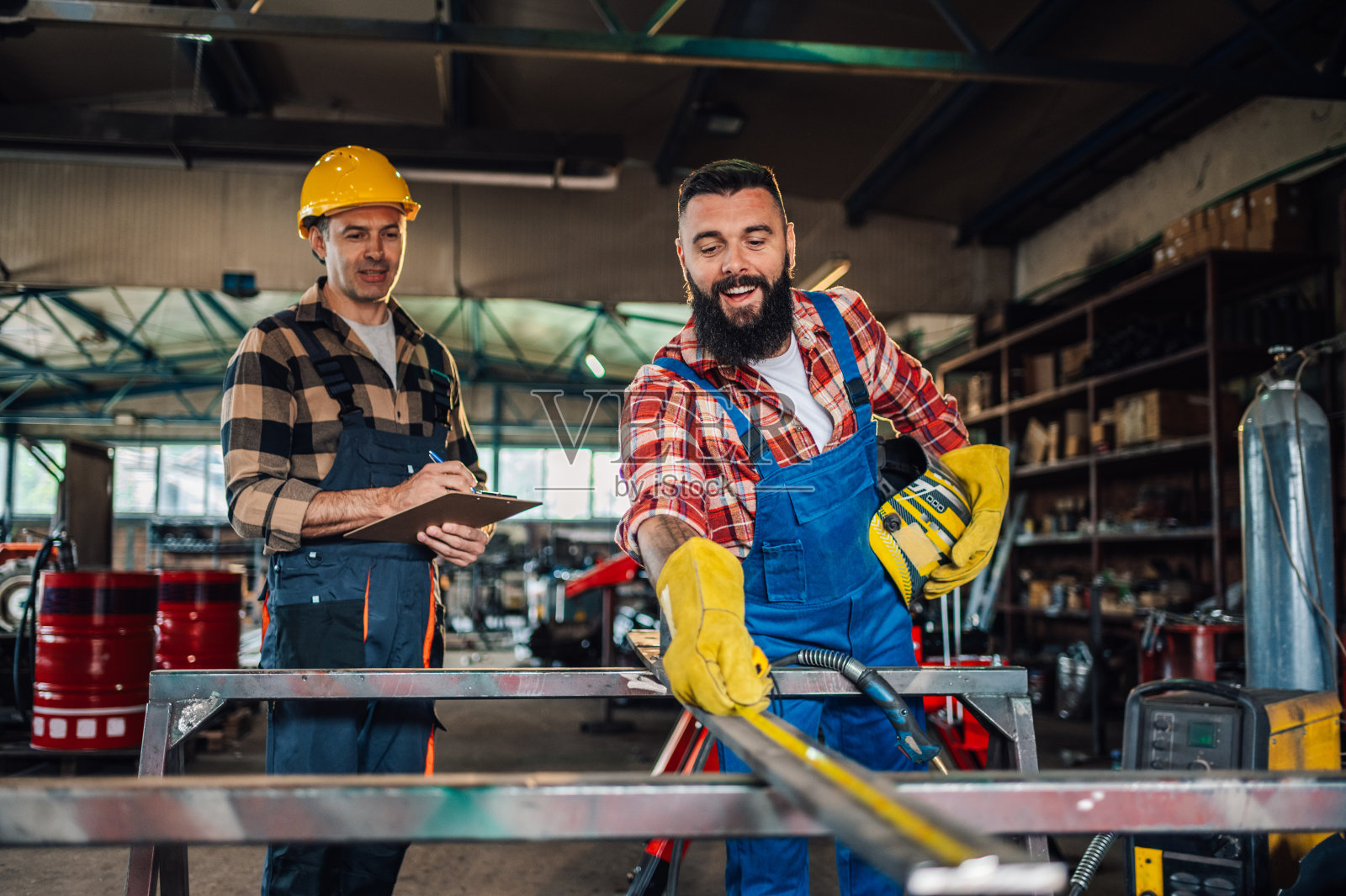 当他的同事在做笔记时，微笑的年轻人正在采取措施。照片摄影图片