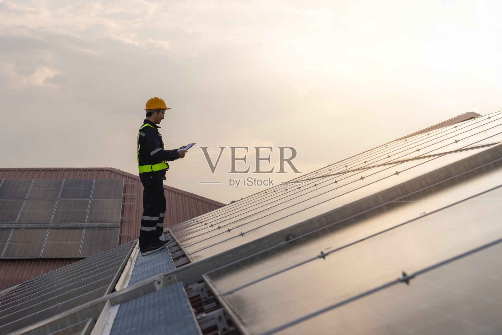 检查屋顶太阳能电池维护的技术。服务工程师安装太阳能电池板。清洁能源理念。照片摄影图片