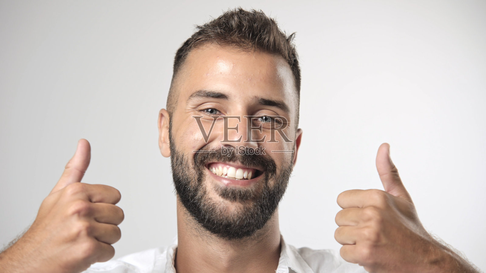 快乐的人微笑，竖起大拇指。帅气的欧洲人看着镜头。面对肖像照片摄影图片