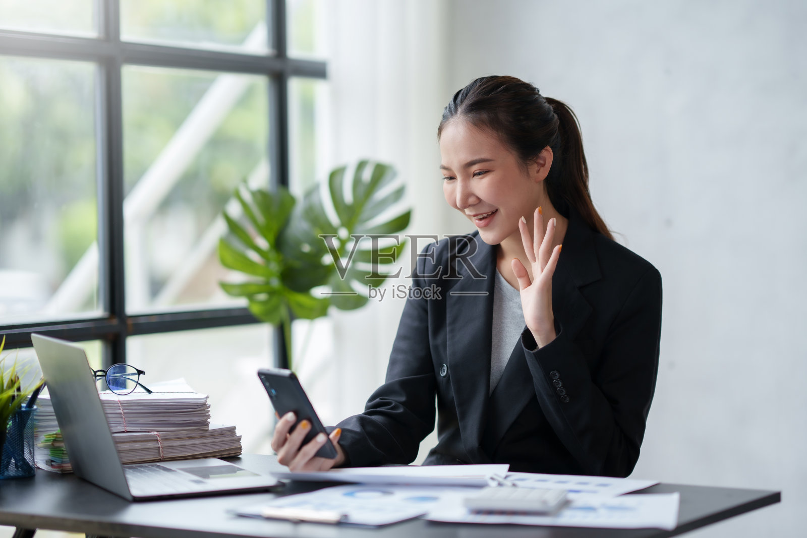可爱的年轻亚洲女商人在工作时用手机与客户通话和视频会议。照片摄影图片
