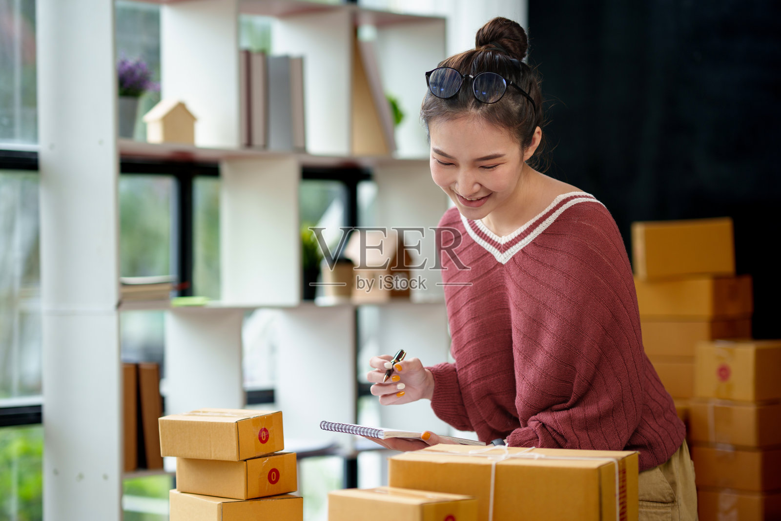 美丽的亚洲在线企业主准备包裹和检查在线订单，在笔记本电脑上检查要发送给客户的余额。网上销售的想法。照片摄影图片