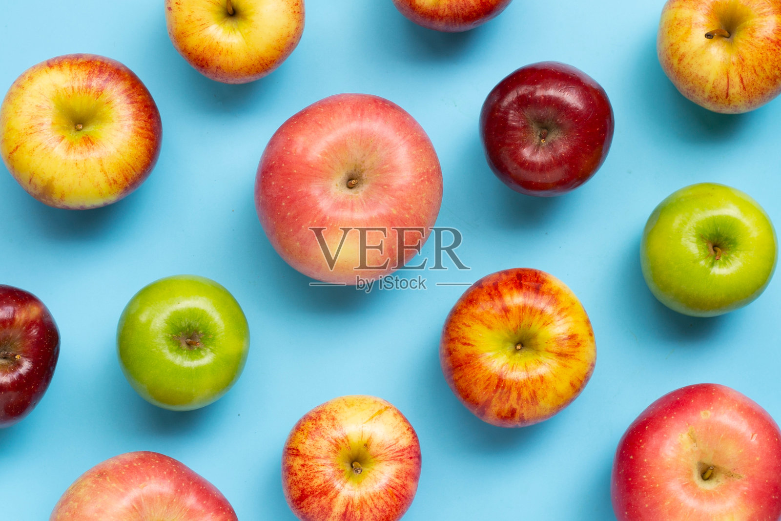 蓝色背景上的各种新鲜苹果。照片摄影图片