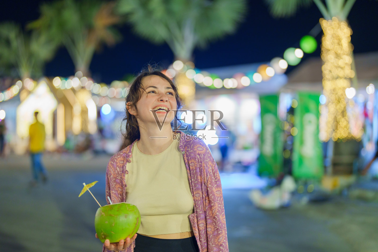 一名女子在曼谷的夜市上吃着椰子冰淇淋照片摄影图片