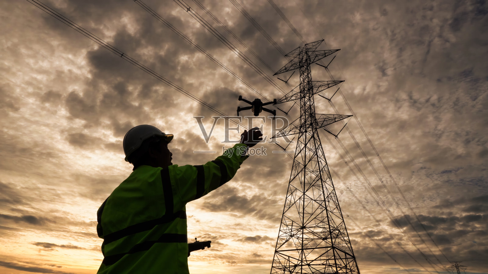 工程师用无人机检查高压电线的剪影。照片摄影图片