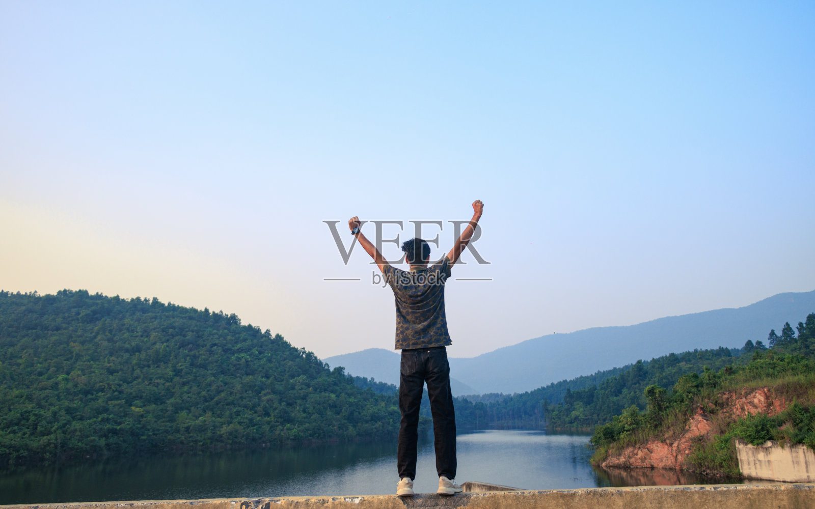 一名男子高举双臂，欣赏山景照片摄影图片