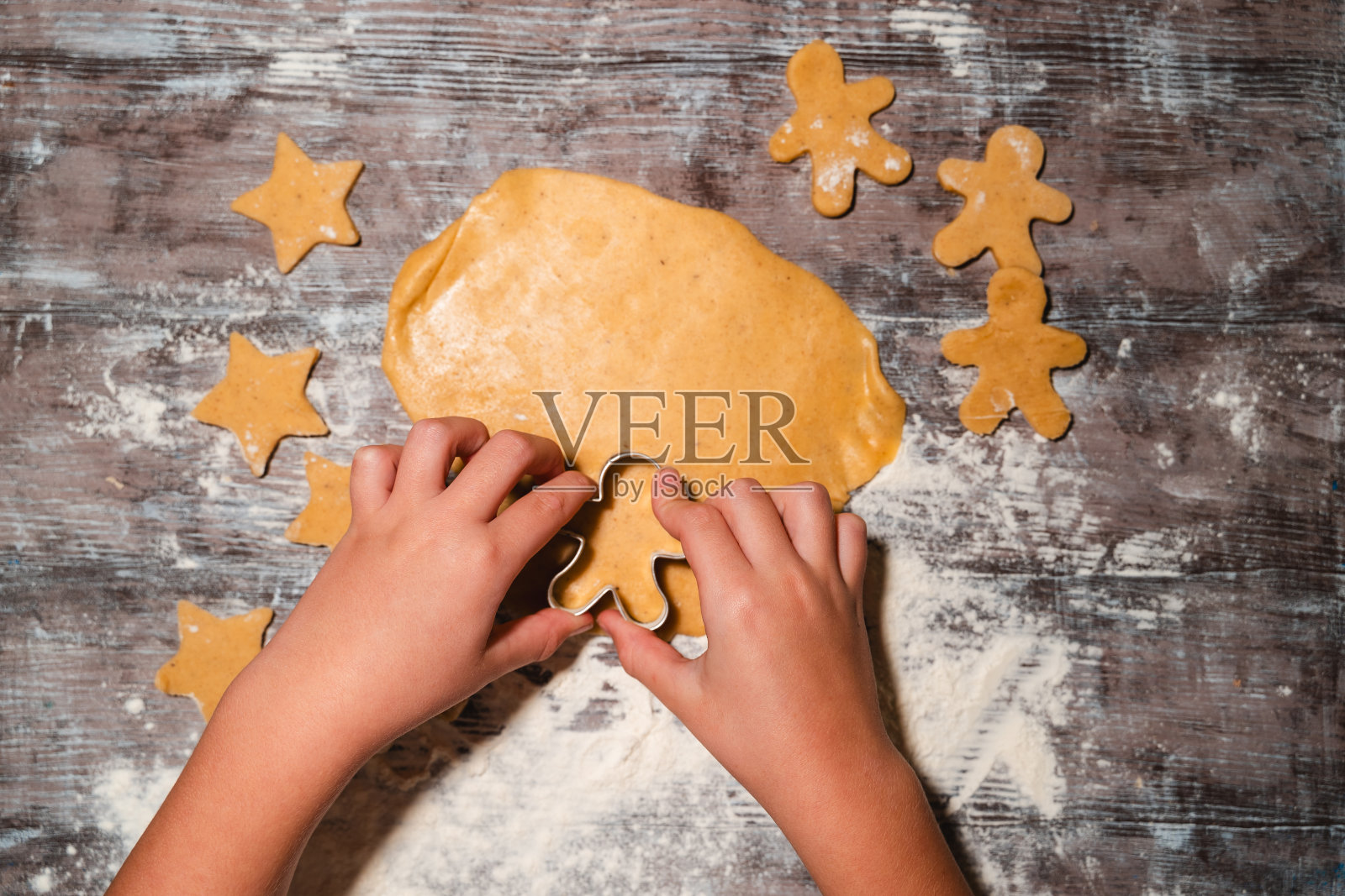 一家人带着孩子在桌上准备撒上面粉的圣诞饼干。照片摄影图片
