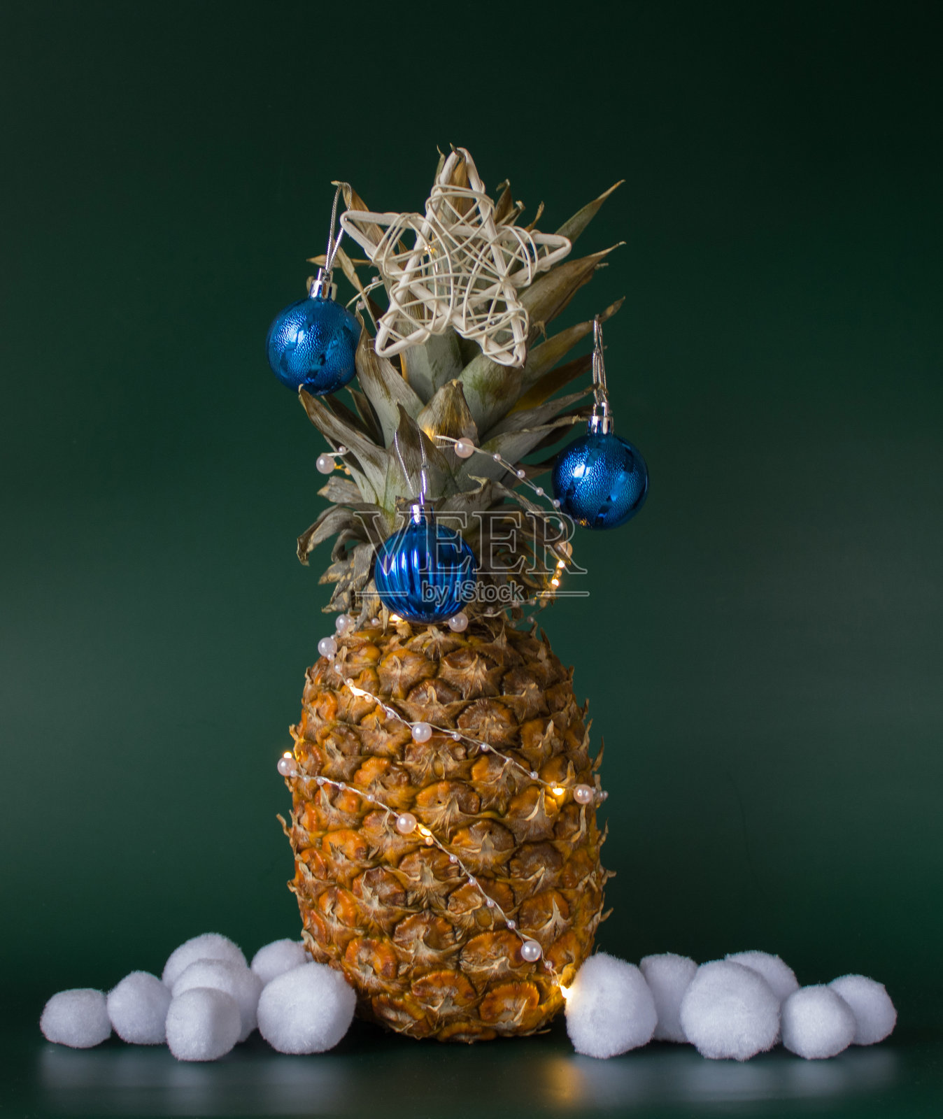 圣诞装饰概念与菠萝，蓝色的球，白色的星星和人工雪球在绿色的背景。本空间照片摄影图片