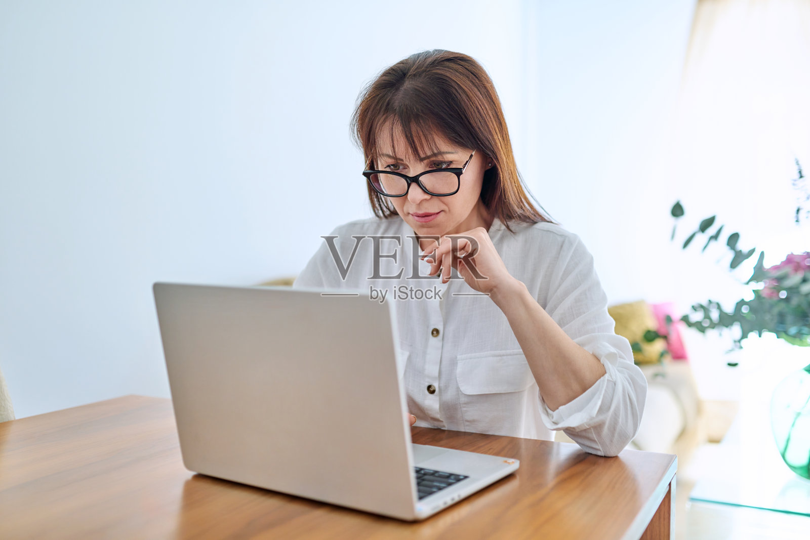 严肃的中年女性，在家办公室用笔记本电脑工作照片摄影图片