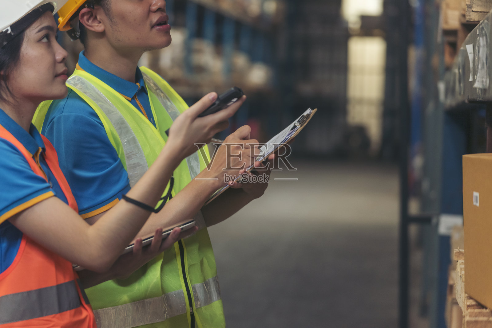 仓库管理团队检查库存情况。亚裔男女工人用条码扫描器扫描货架上的商品，在剪贴板上写清单。配合物流人员清点产品库存照片摄影图片