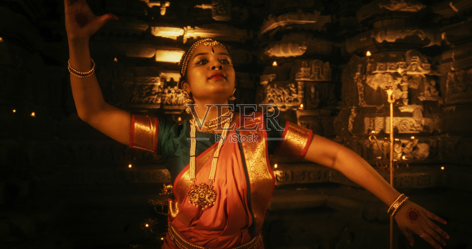 年轻印度女子在烛光寺庙中表演传统民族舞蹈的动态照片，展现迷人的文化照片摄影图片