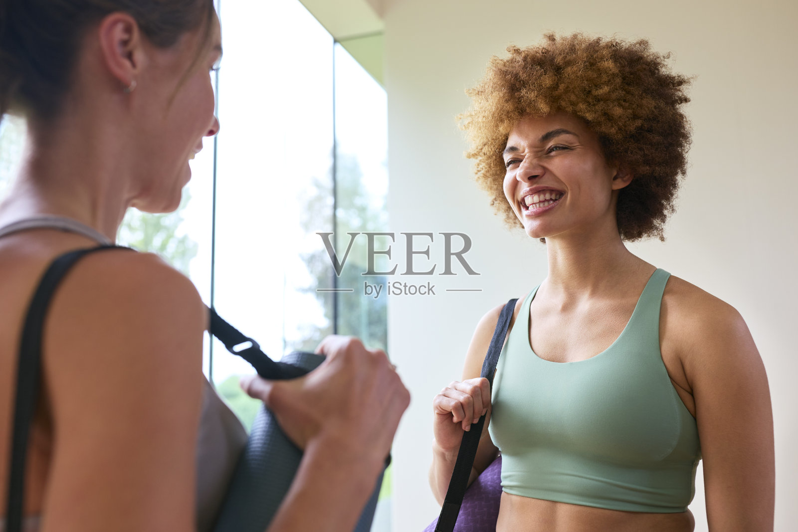 两个穿着运动服的女性朋友在健身房或瑜伽馆见面锻炼照片摄影图片