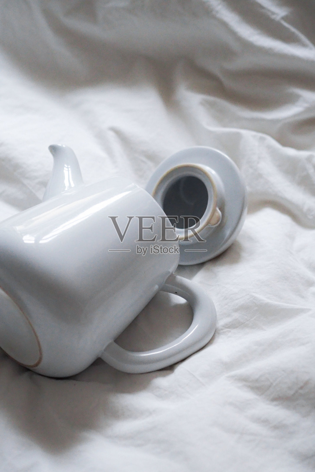 白色陶瓷茶壶放在床单上照片摄影图片