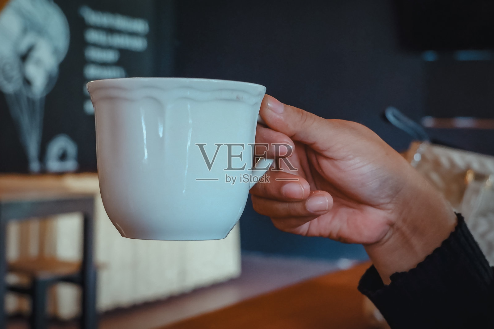 咖啡馆里，女性手端咖啡照片摄影图片