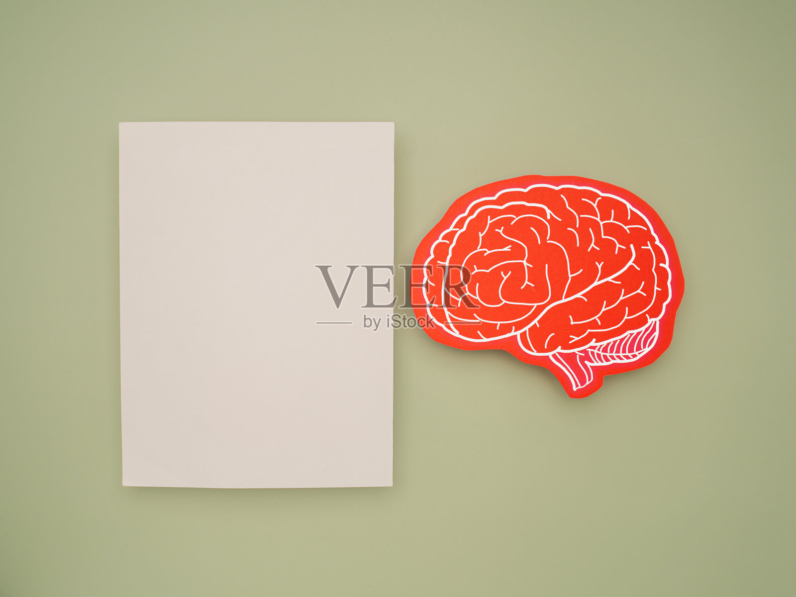 一张空白的白纸和一个绿色背景上的红色脑形符号照片摄影图片