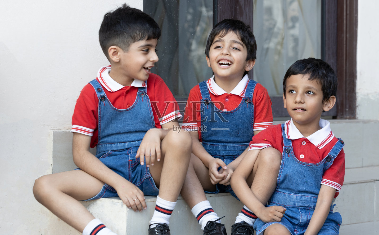 快乐的印度男孩学生坐在学校外面。教育的概念。照片摄影图片