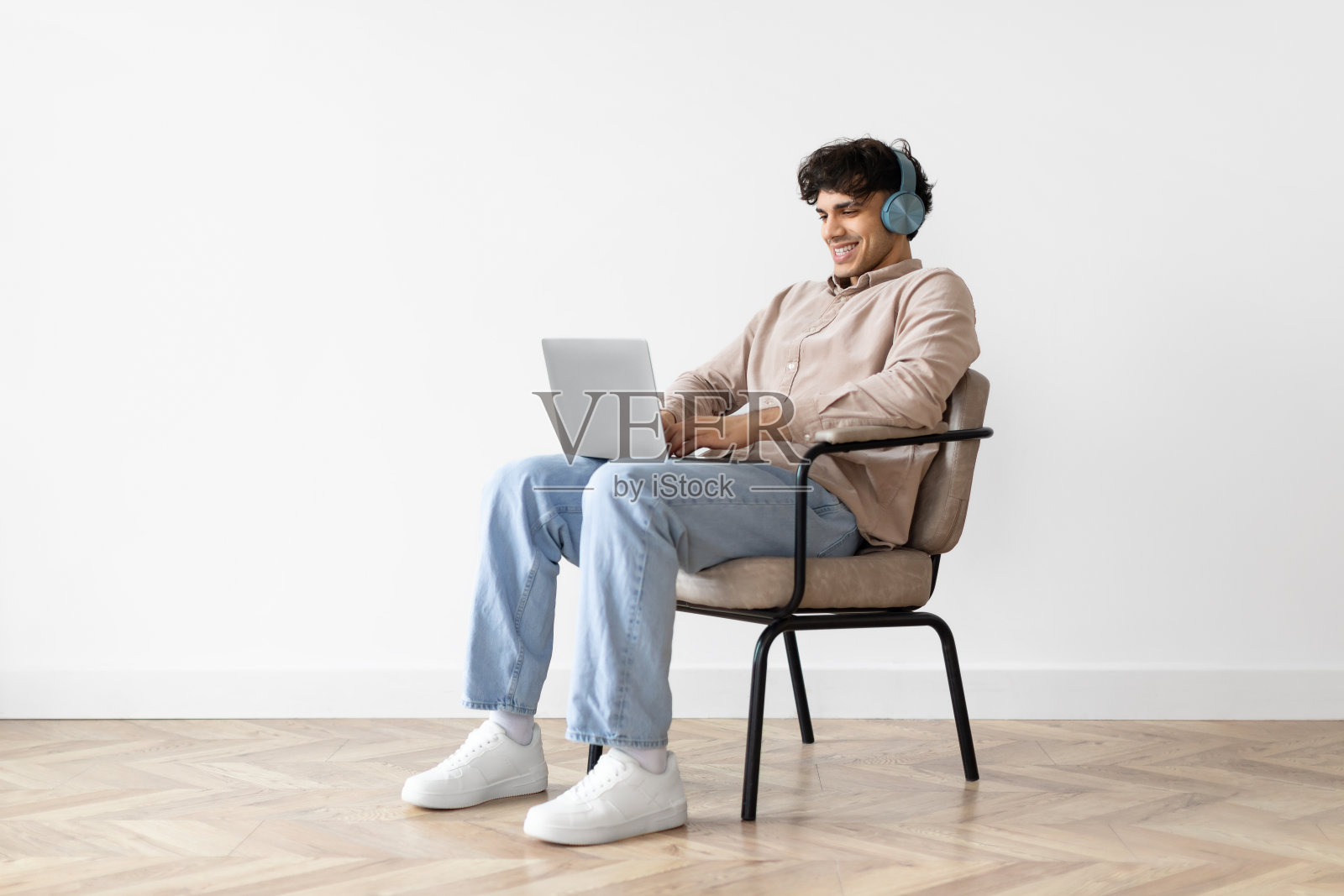 阿拉伯人用笔记本电脑上网，戴着耳机坐在室内照片摄影图片