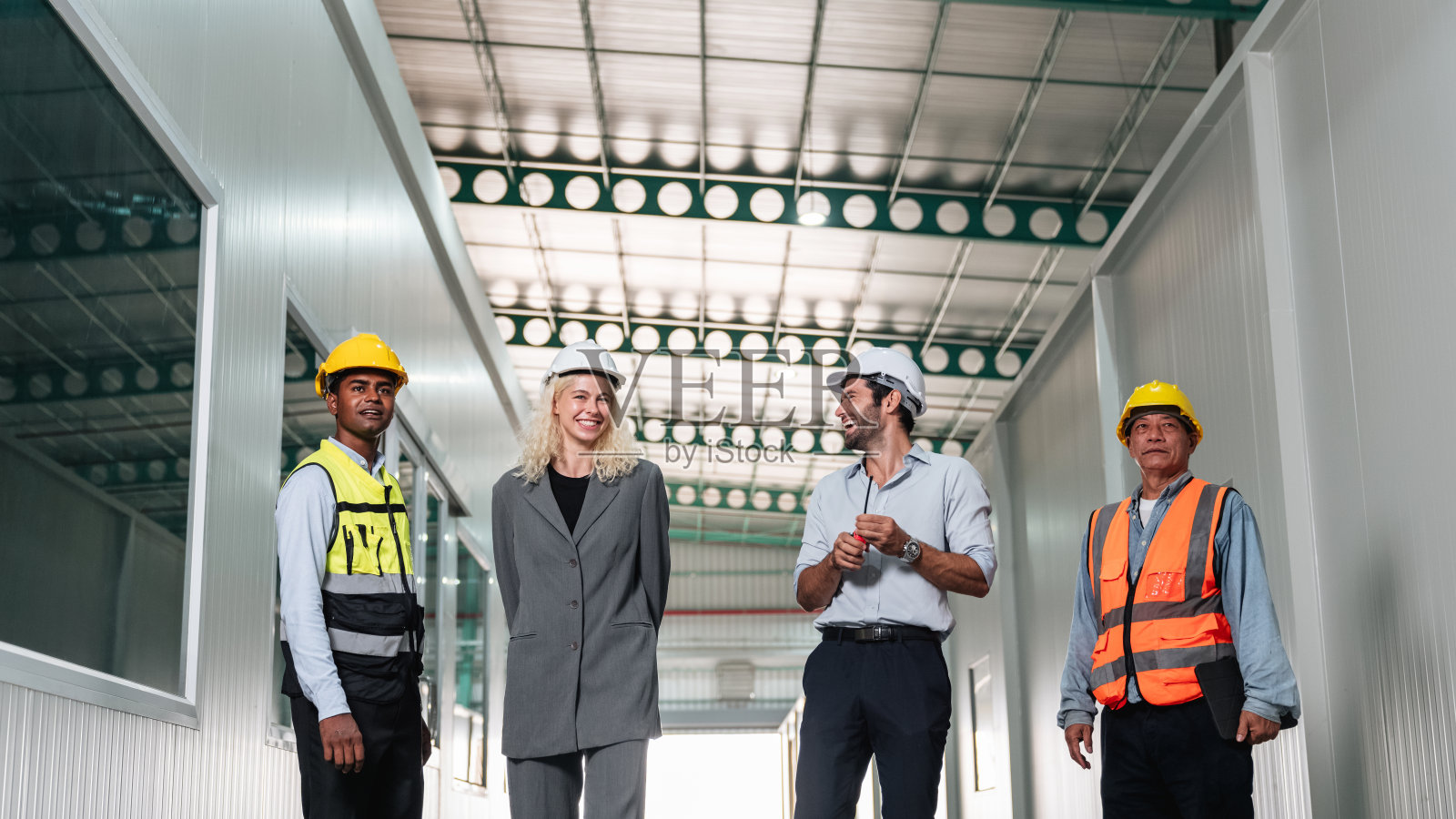 团队工程师和工人在空仓库中进行计划和讨论，设计产品货架布置，组织新制造策略。照片摄影图片