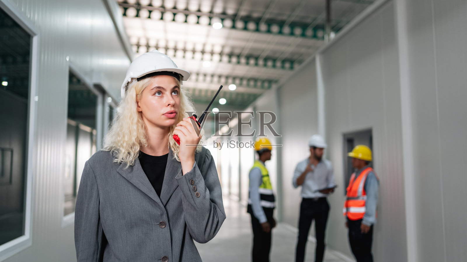 图为工程师和工人在空荡荡的仓库里用对讲机设计产品货架的布置。照片摄影图片
