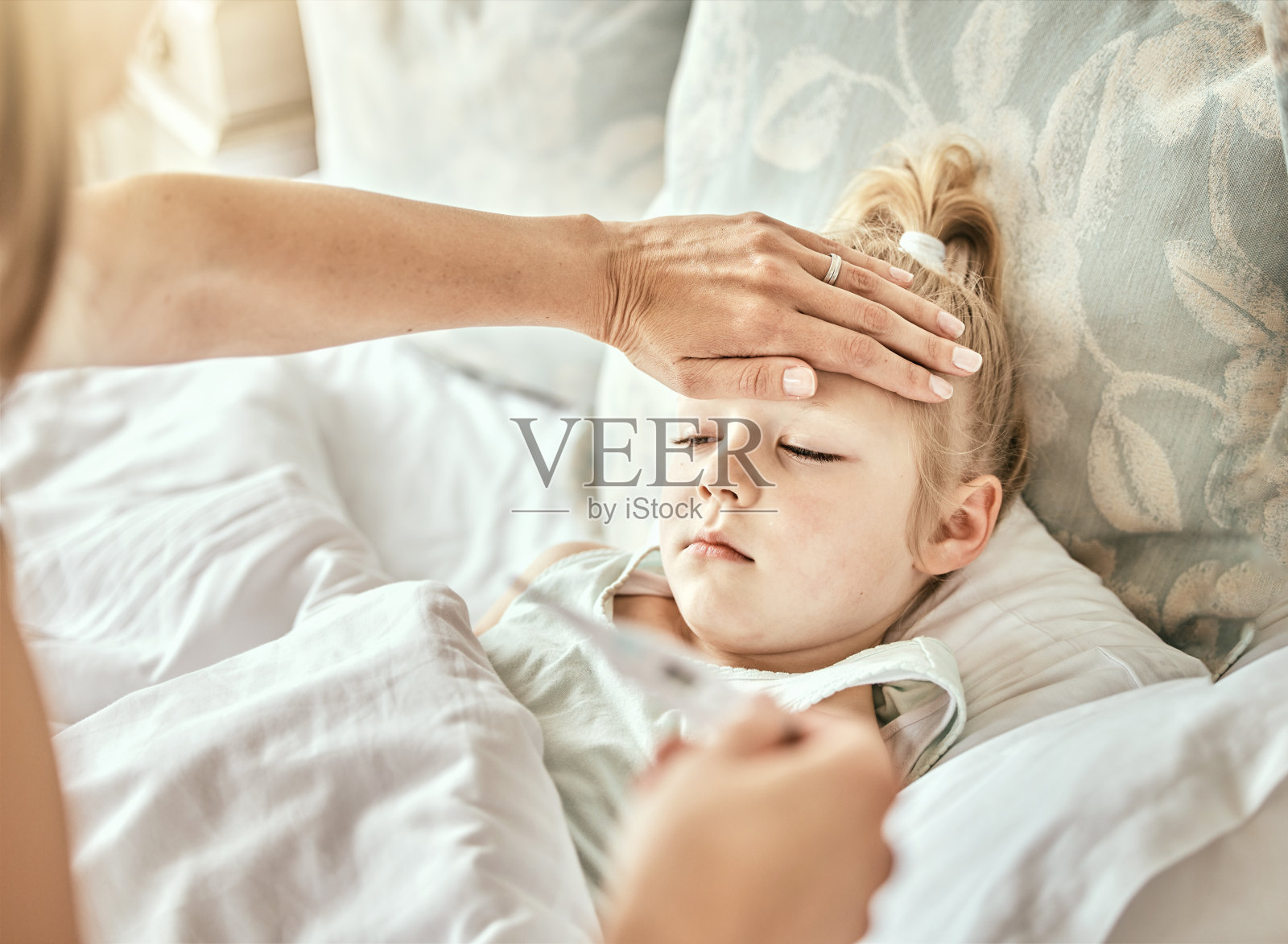 父母，手和体温计与生病的孩子，发烧或流感病毒在床上从家里感冒。母亲在卧室或家中休息时为生病的孩子检查体温或测量的特写照片摄影图片