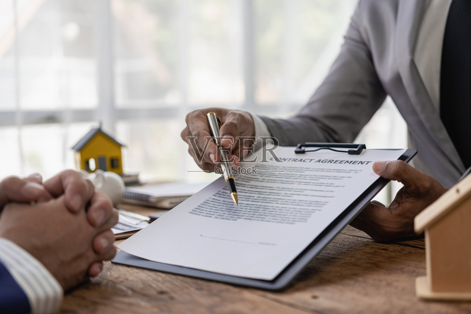 房地产经纪人讨论购房合同的条款，并要求客户签署合法签订合同的文件。卖房子。特写照片。照片摄影图片