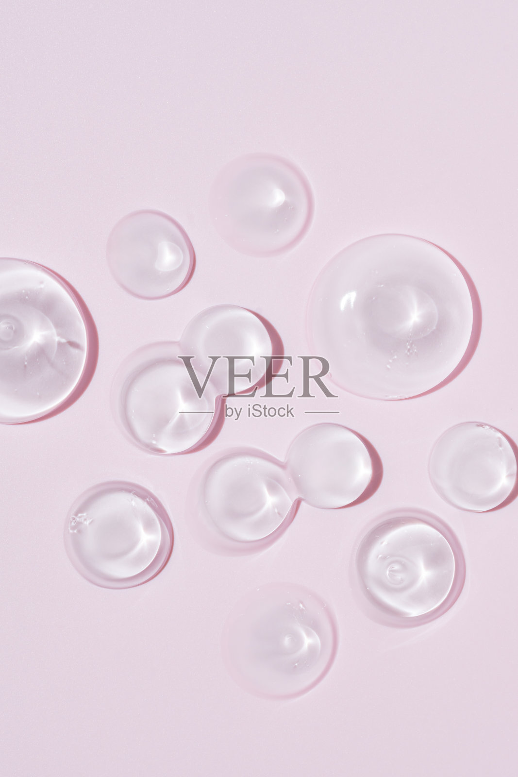 甘油凝胶质地。透明血清滴在粉红色的背景。液体凝胶保湿与泡沫宏观照片摄影图片