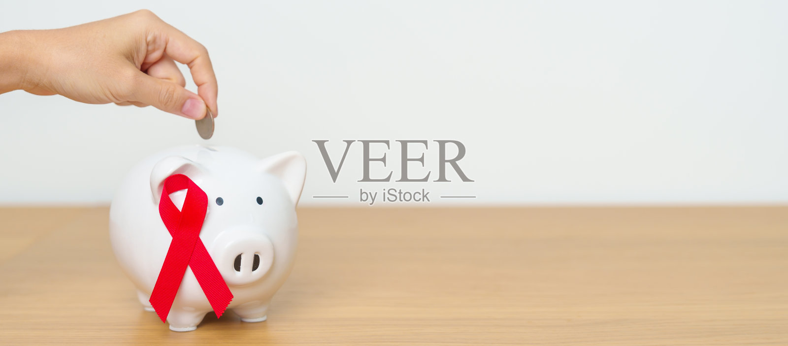 12月世界艾滋病日，获得性免疫缺陷综合征，红丝带与存钱罐一起支持疾病生命。健康、捐赠、慈善、运动、省钱、基金和世界癌症日的概念照片摄影图片