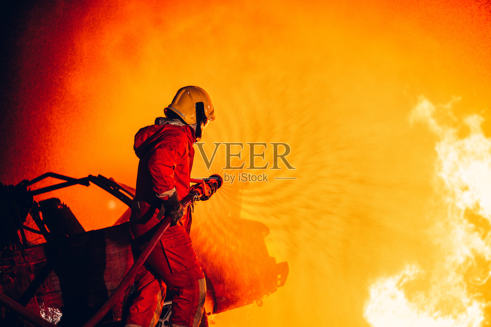 无畏的消防员用水和灭火器灭火。行动中的消防员，以团队精神和勇气灭火。激烈的消防训练演习。照片摄影图片