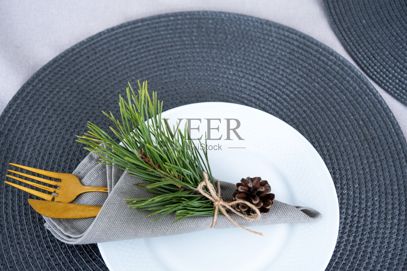 用盘子、刀叉、餐巾纸摆上节日的餐桌，特写的纸巾放在一个装饰着圣诞节和新年的松枝上。Eco-style,极简主义照片摄影图片