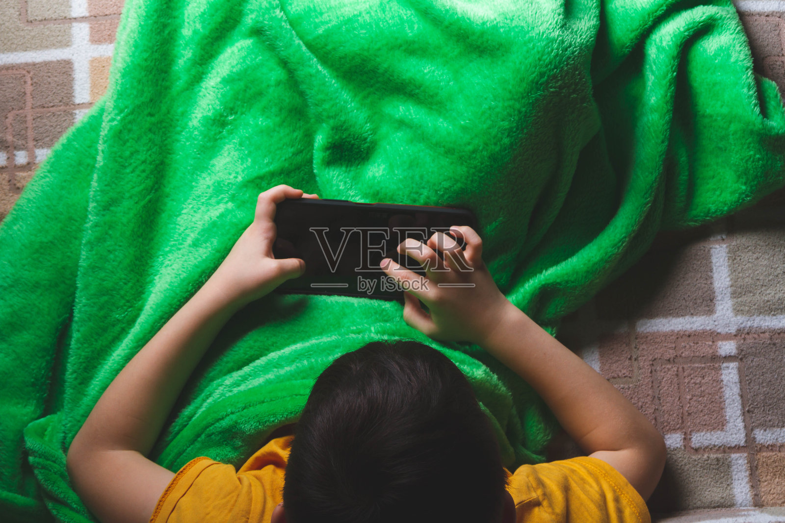 孩子手里拿着电话。小男孩在玩手机游戏。手的特写镜头。照片摄影图片