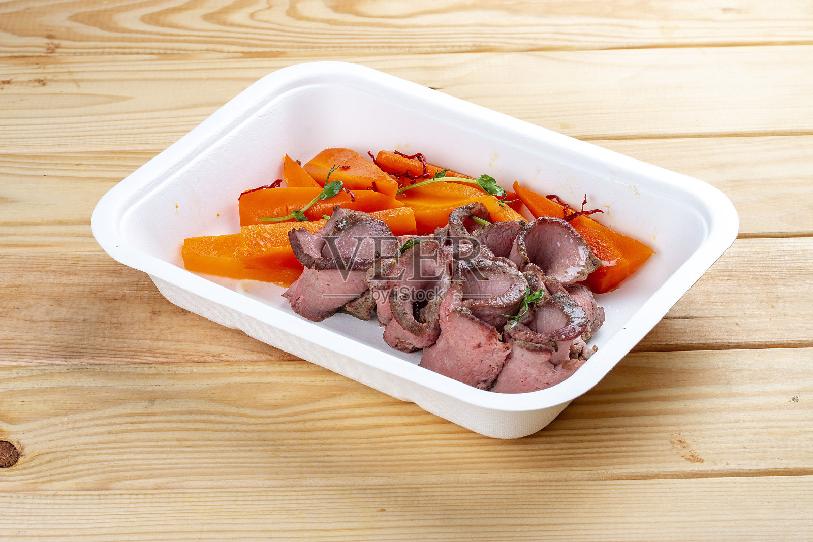 炖牛肉配多汁胡萝卜。健康的饮食习惯。外卖食物。生态包装。在木制背景上。照片摄影图片