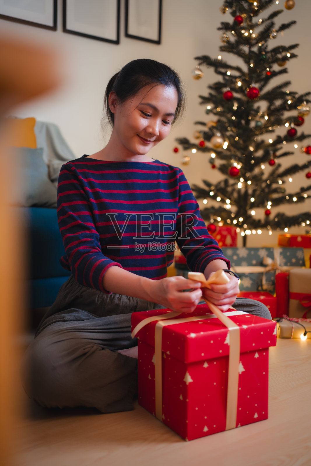 为圣诞节包装礼物的亚洲妇女。照片摄影图片