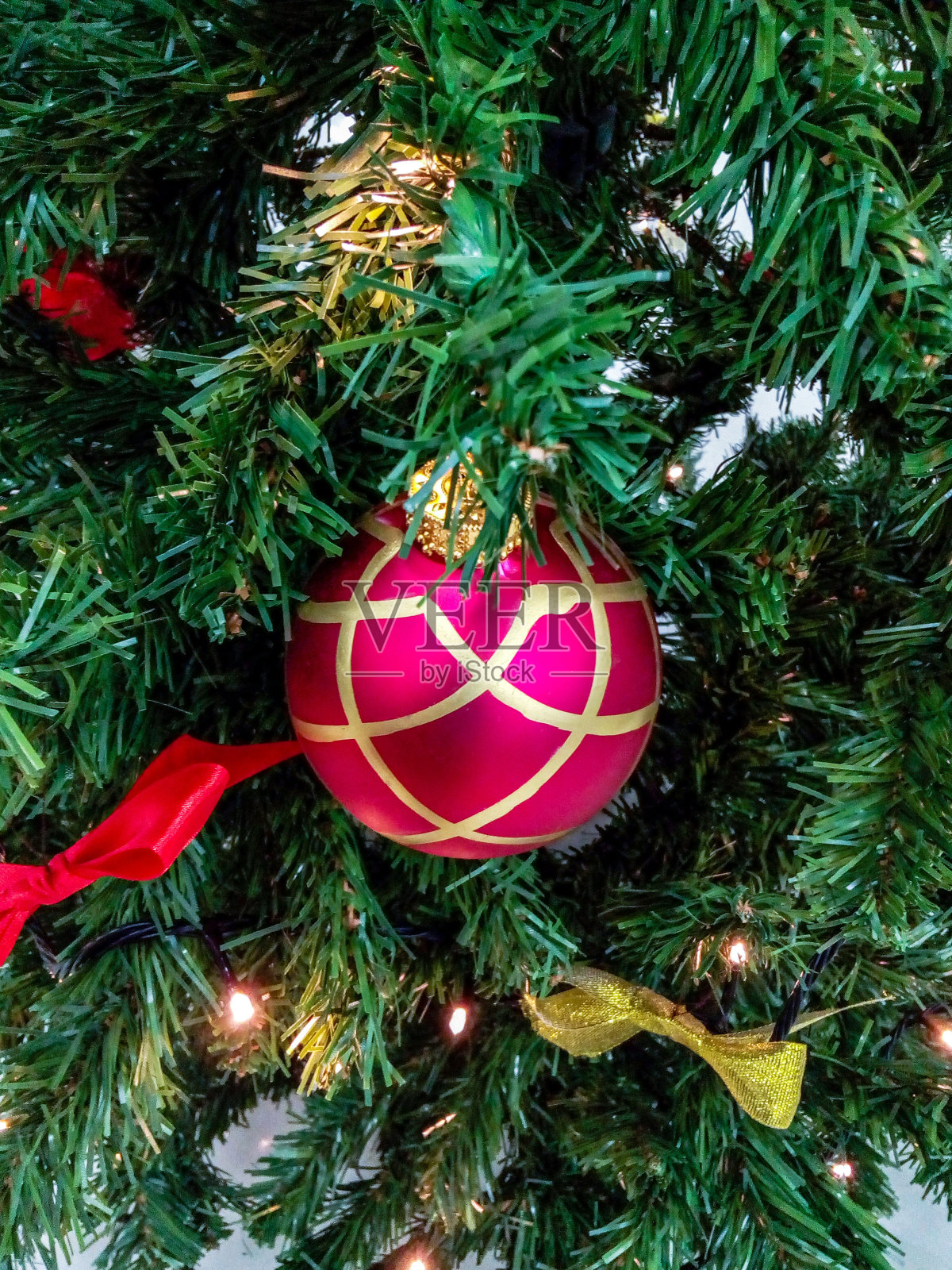 五彩缤纷的圣诞玩具在人造圣诞树上:球，弓和花环灯。新年饰品，复古装饰。照片摄影图片