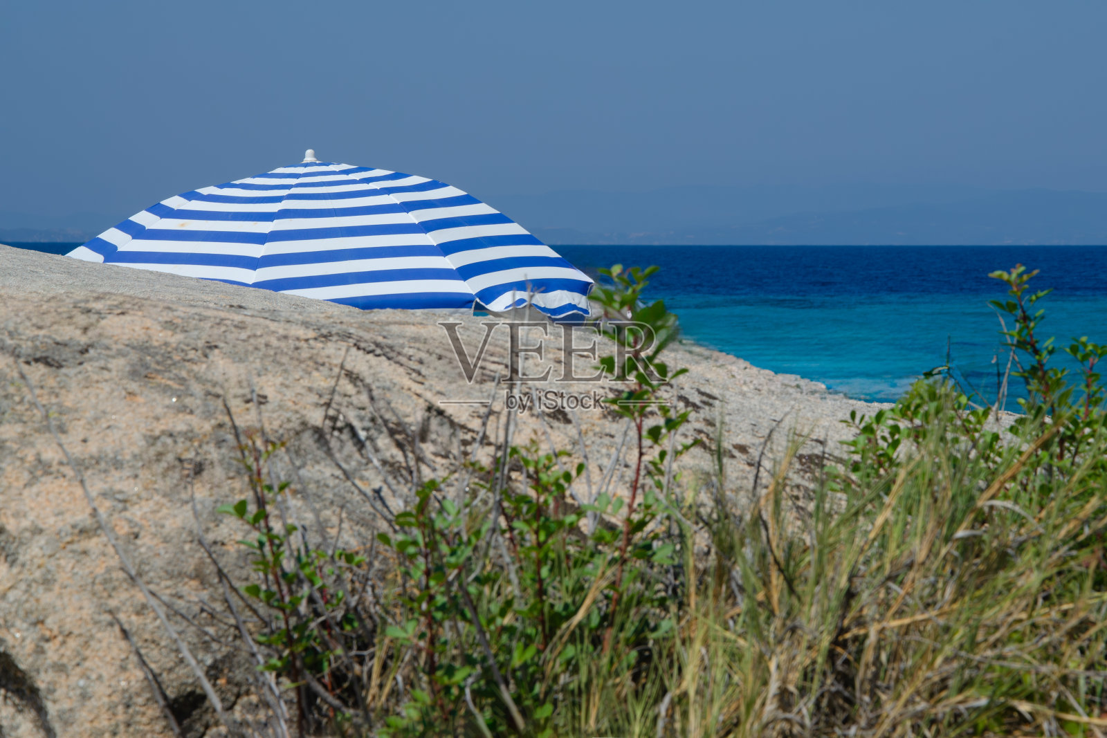沙滩伞背后的岩石在大海的背景照片摄影图片